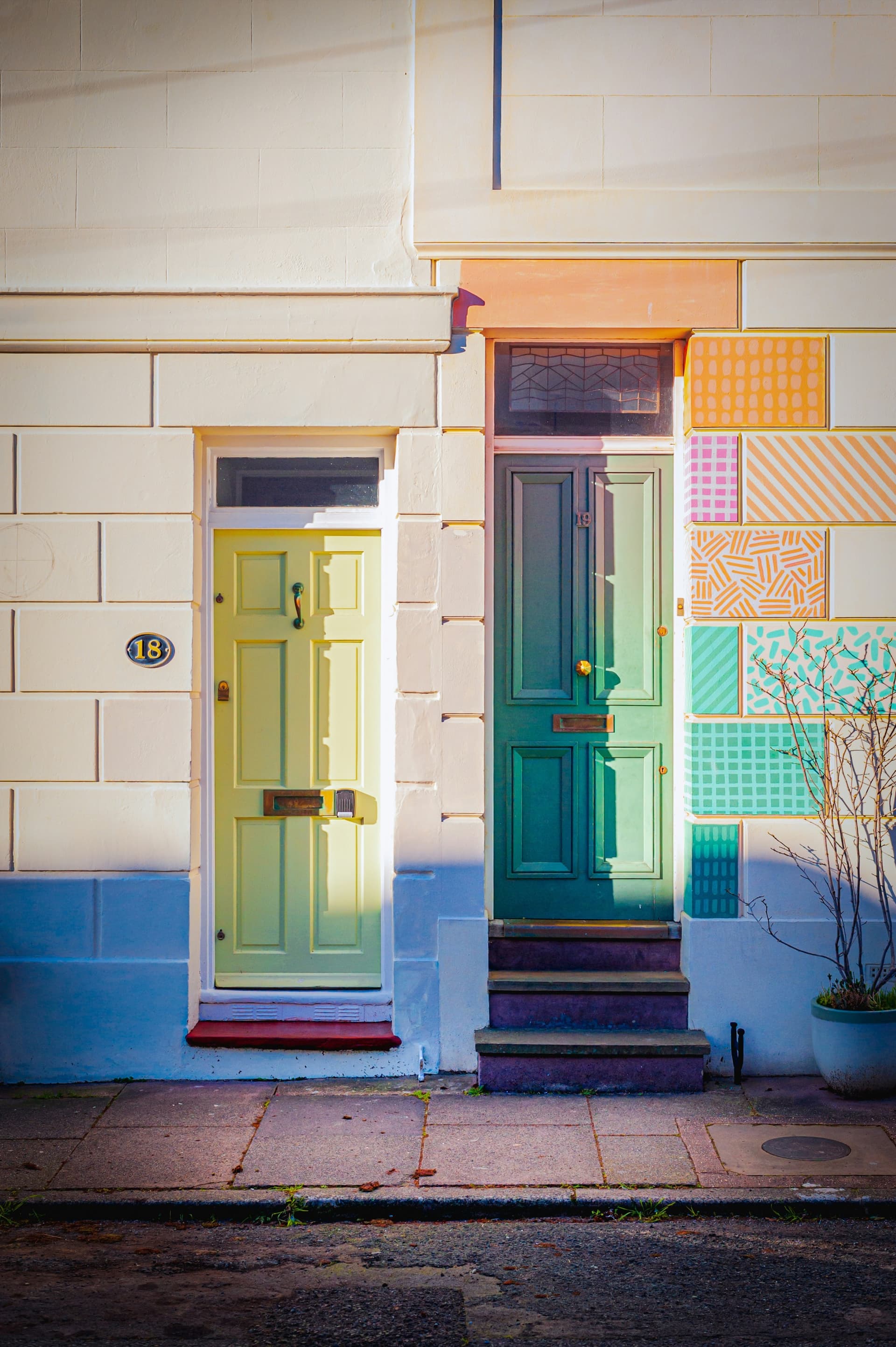 Two pastel front doors, green and teal, on a Brighton terrace