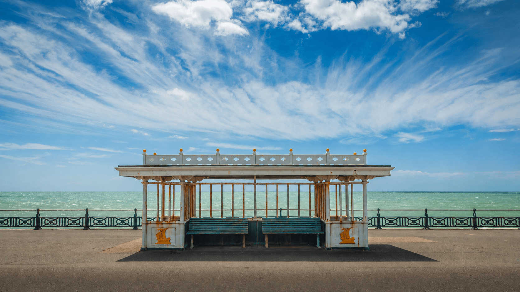 A Victorian seafront shelter against a wide blue sky
