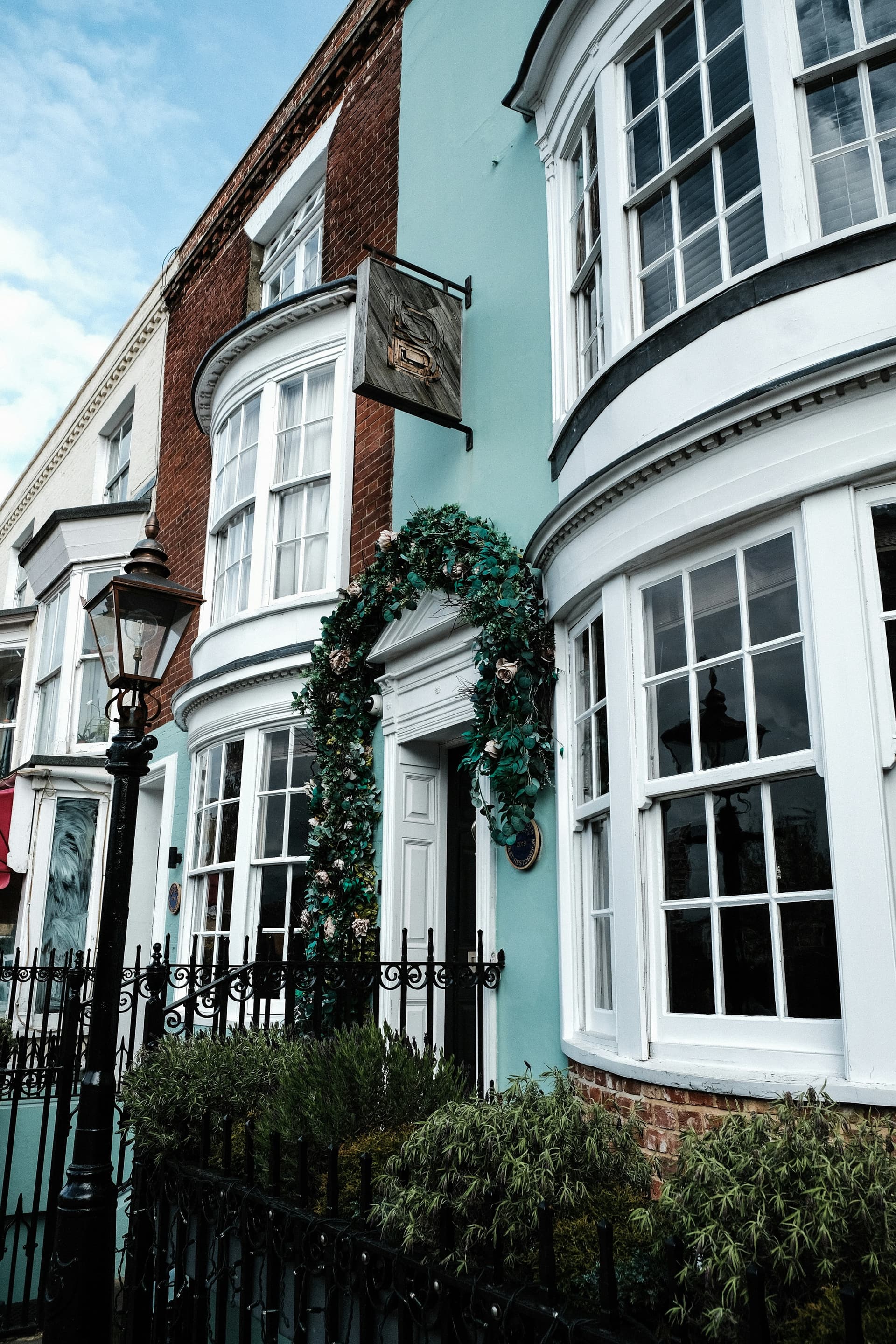 A mint-green bow-fronted Sussex townhouse with a flower garland around the door