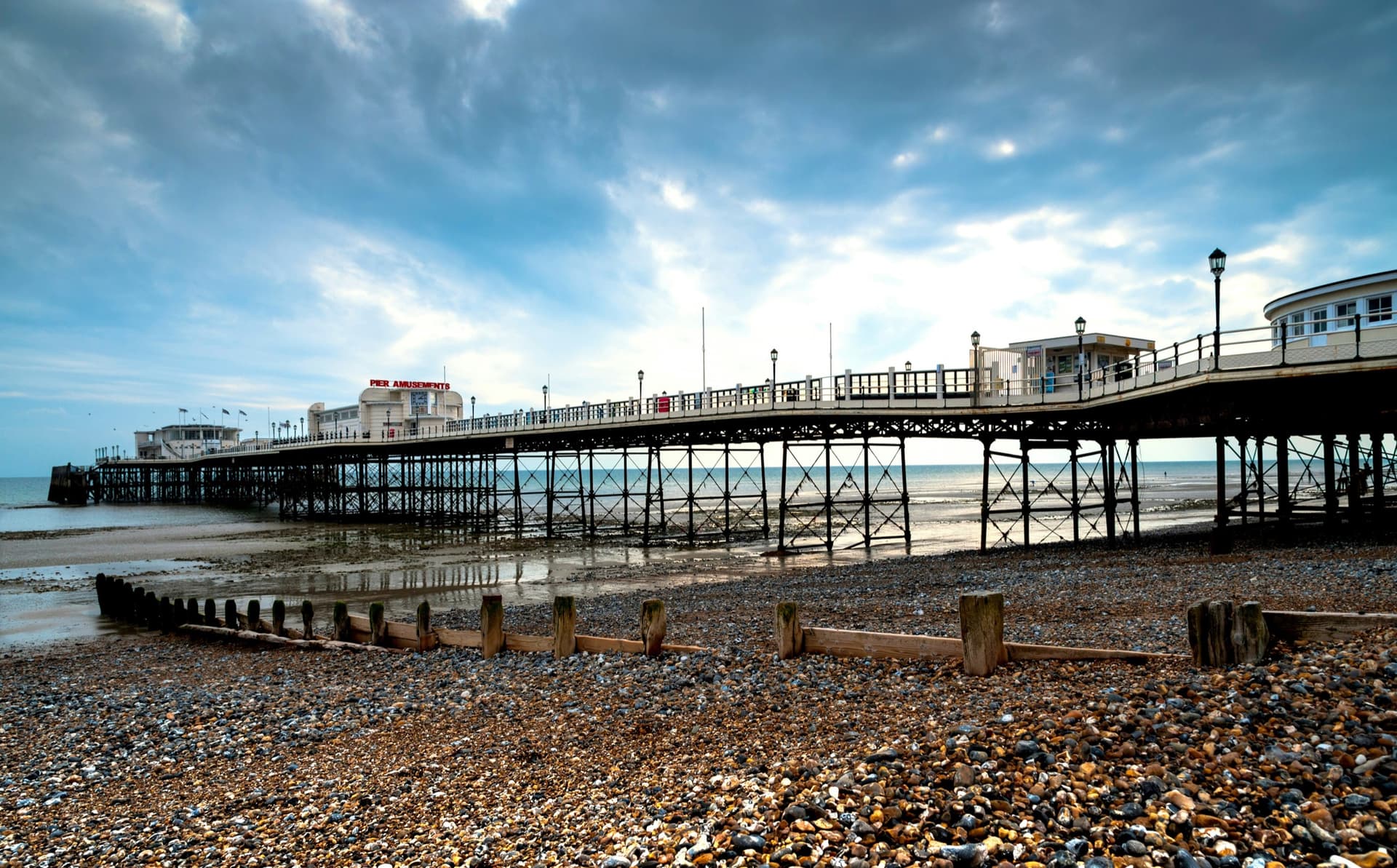 Worthing pier from the pebble beach under a wide sky