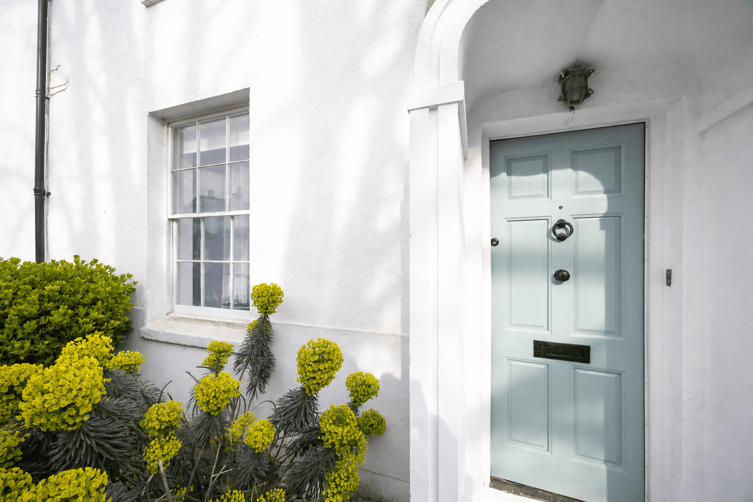 The white exterior and pale blue front door of the historic Worthing townhouse