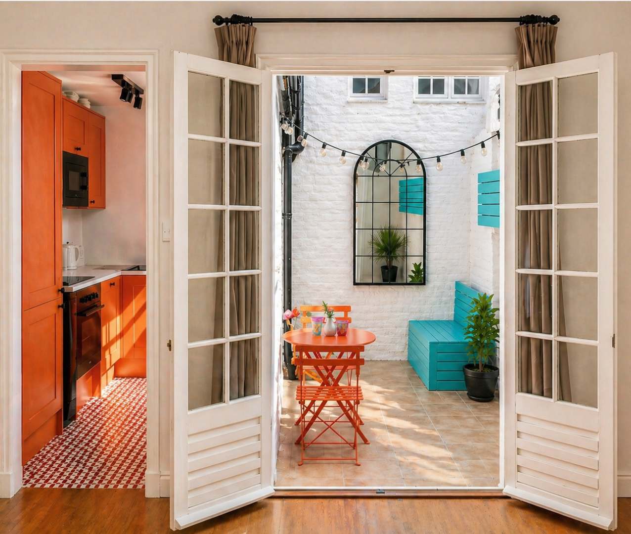 Open French doors framing a sunny courtyard with orange and turquoise furniture