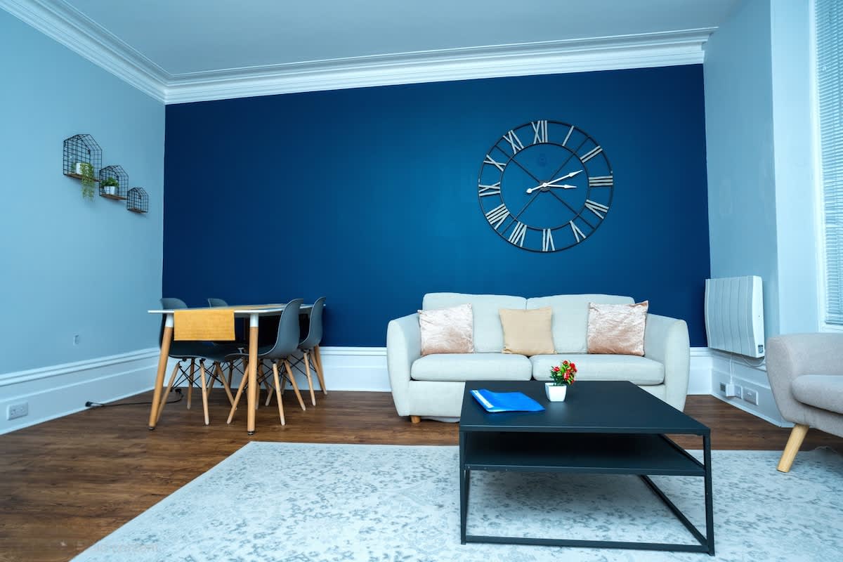 Deep blue sitting room with a pale sofa and dining table at a South House Brighton home