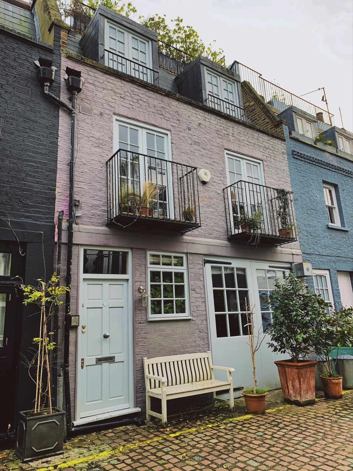 A painted family house with balconies and planting on a quiet residential street