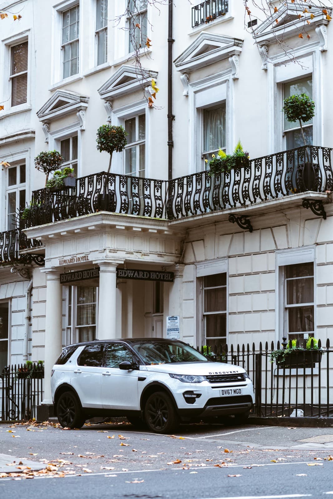 A white stuccoed building with wrought-iron balconies and planting above