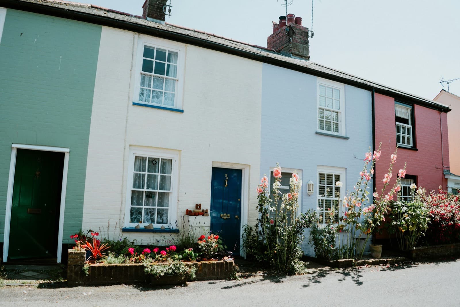 A row of pastel-painted period cottages with flowers in the front gardens