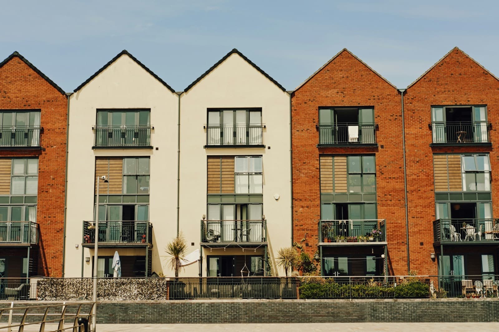 A row of modern brick townhouses with balconies beside water